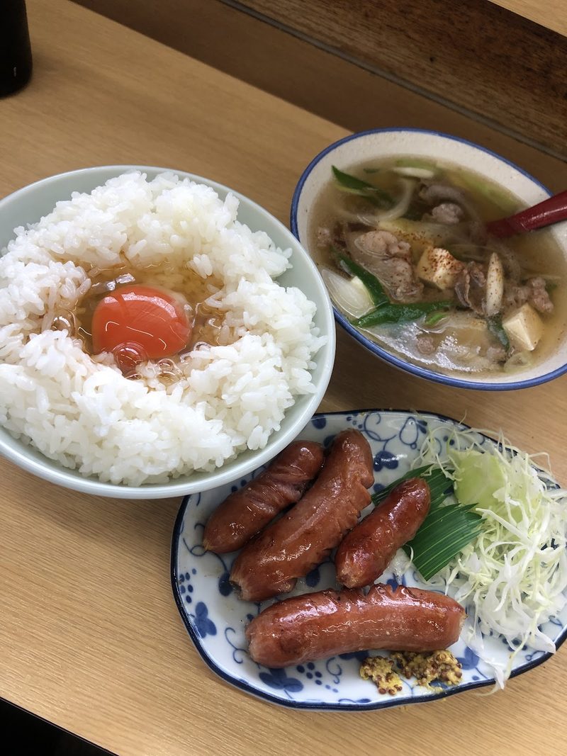 生卵をのせたご飯と赤いウインナー、汁物